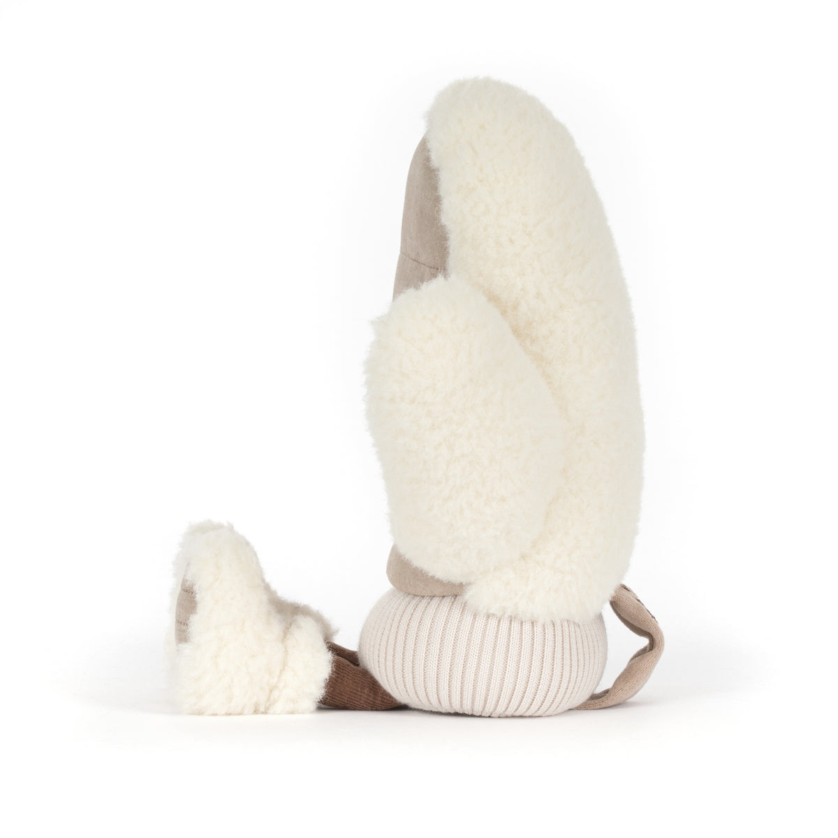 Jellycat Amuseables Fitswell Mitten Fäustling in Beige, sitzend mit kleinen Füßen in Winterboots, flauschigem Rand von der Seite