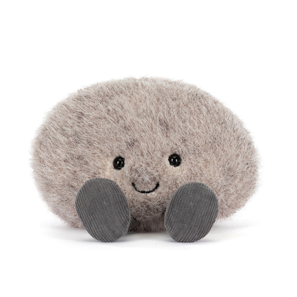 Jellycat Amuseables Pebble sitzt entspannt mit ausgestreckten Füßen und sanftem Lächeln – ein ruhiger, kleiner Kuschelbegleiter