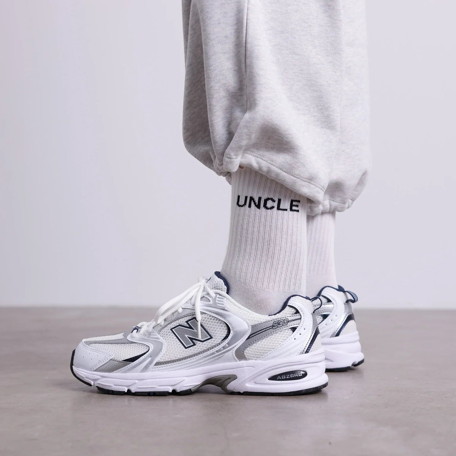 Weiße UNCLE Socken mit schwarzem Schriftzug, klassisches Socken-Design aus Baumwollmischung, flach liegend fotografiert.