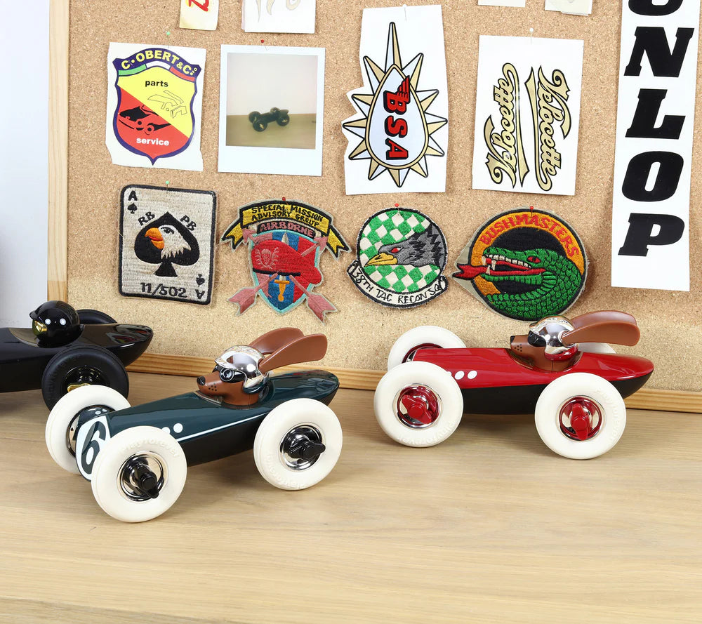 Rotes Rufus Spielauto mit Startnummer 3, weißen Gummireifen, stromlinienförmigem Design und Hundemotiv.