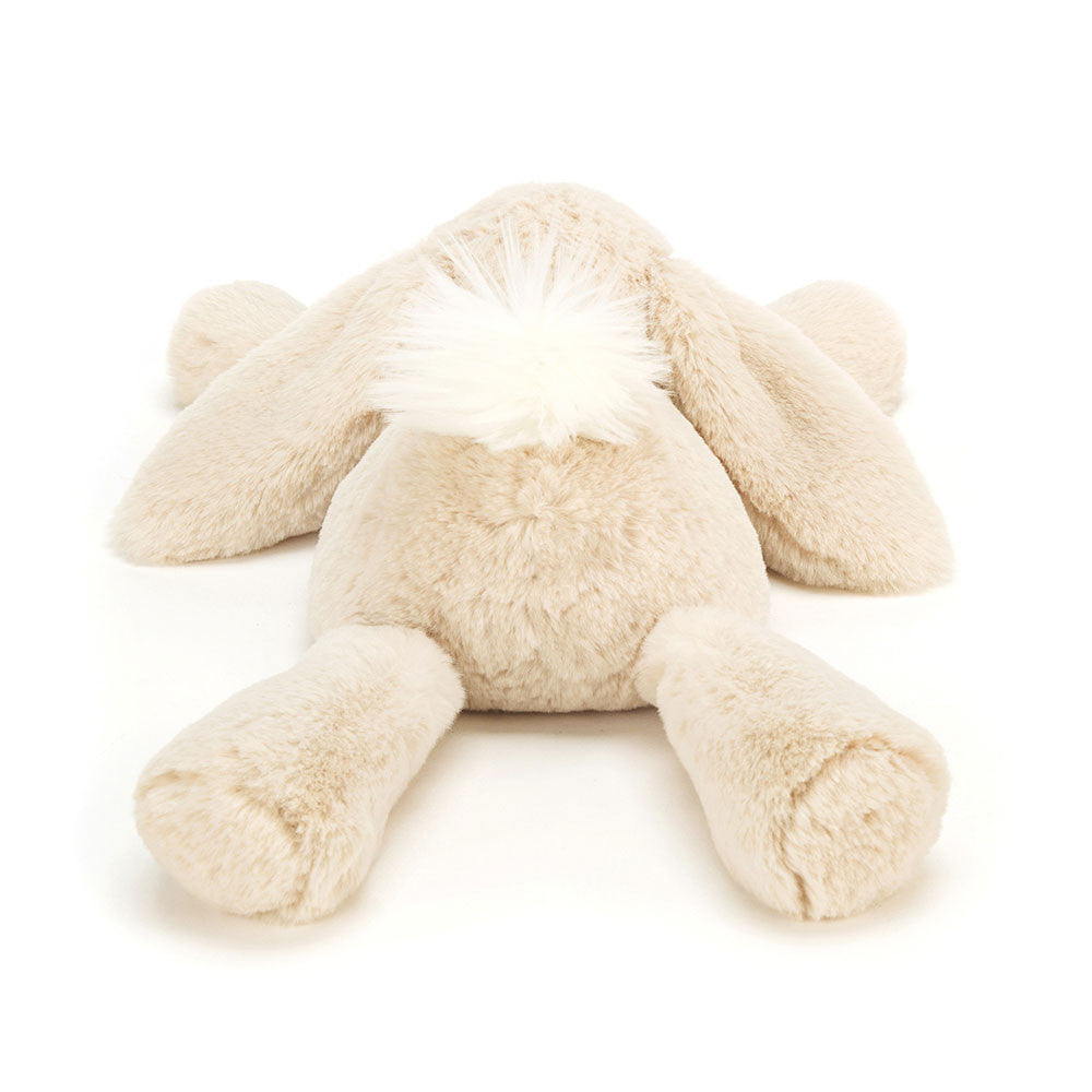Rückansicht: Jellycat Smudge Rabbit – liegender hellbeiger Kuschelhase mit langen Hängeohren, ausgestreckten Beinen und Kopf auf den Vorderpfoten. Mit kleinen schwarzen Knopfaugen und weißem Puschelschwanz.