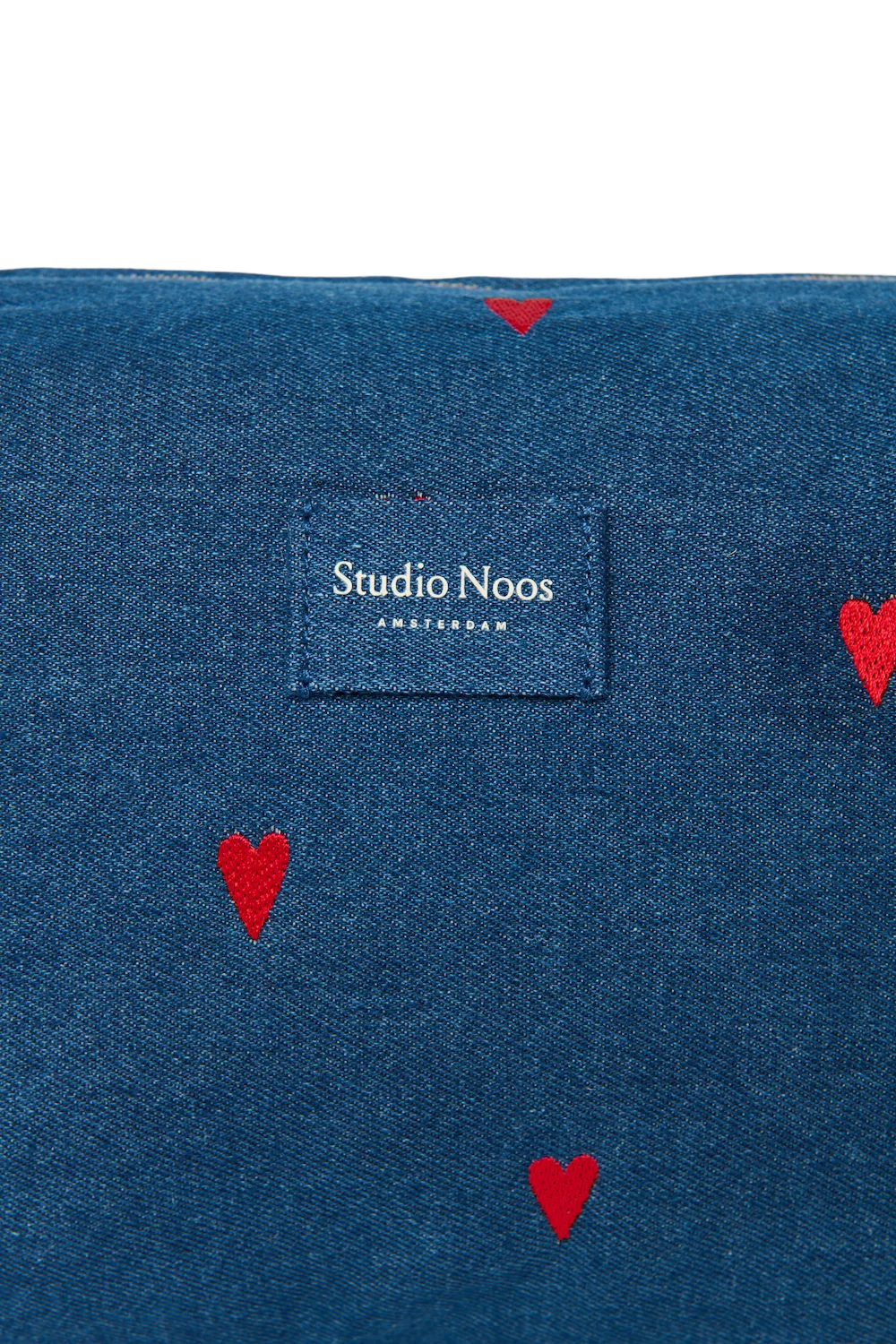 Detailansicht des Studio Noos Logos auf der dunkelblauen Kosmetiktasche Bag mit gestickten roten Herzen