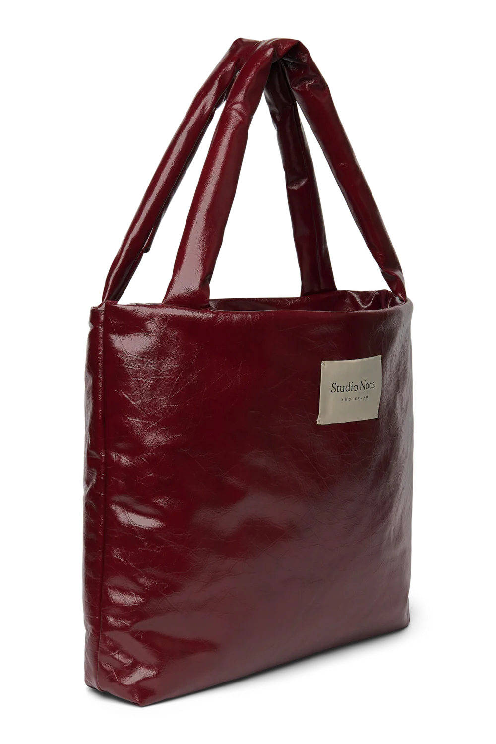 Seitenansicht: Studio Noos Vegan Leather Mom Bag in Bordeauxrot mit gepolsterten Griffen und kleinem Studio Noos Amsterdam Label vorne