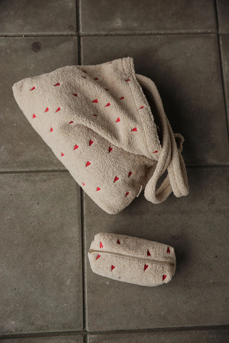 Mit Herzen bestickte Kulturtasche aus Teddystoff mit passender Mom Bag von Studio Noos.