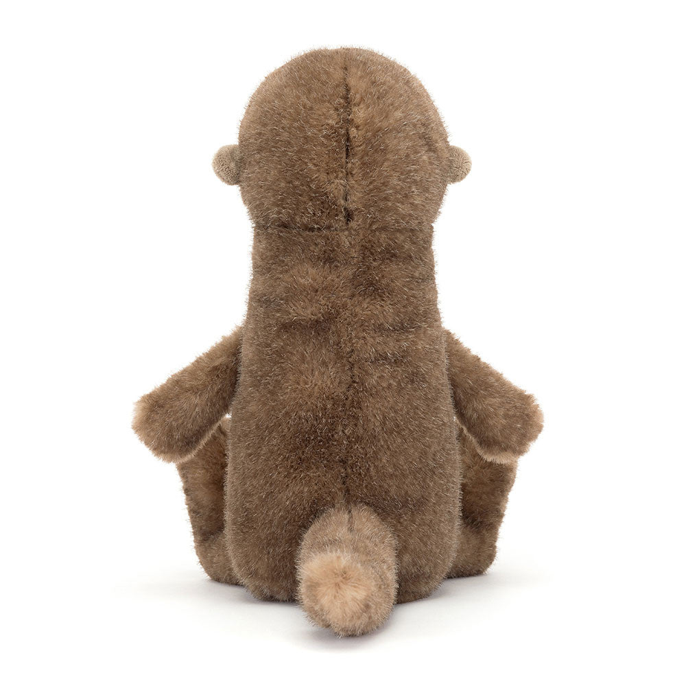 Braunes Jellycat Brooke Otter Kuscheltier sitzt kerzengerade am Ufer und schaut aufmerksam in die Umgebung, wirkt wie ein kleiner Wächter der Flusslandschaft