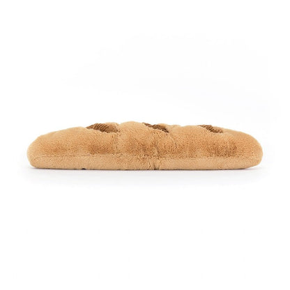 Braunes Plüsch-Croissant mit Lachgesicht streckt kleine beinchen von sich