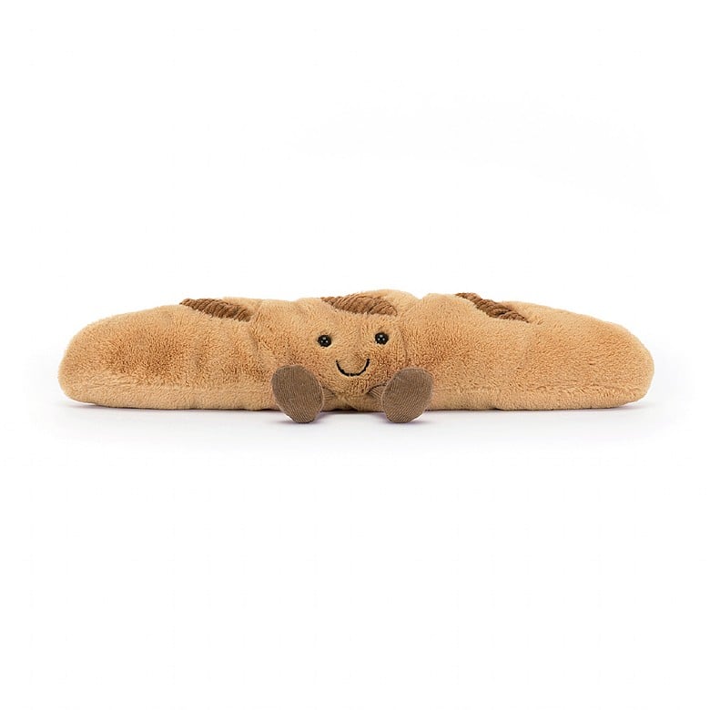 Braunes Plüsch-Croissant mit Lachgesicht streckt kleine beinchen von sich