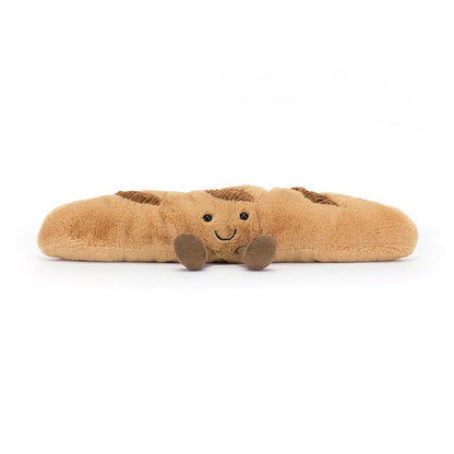 Braunes Plüsch-Croissant mit Lachgesicht streckt kleine beinchen von sich