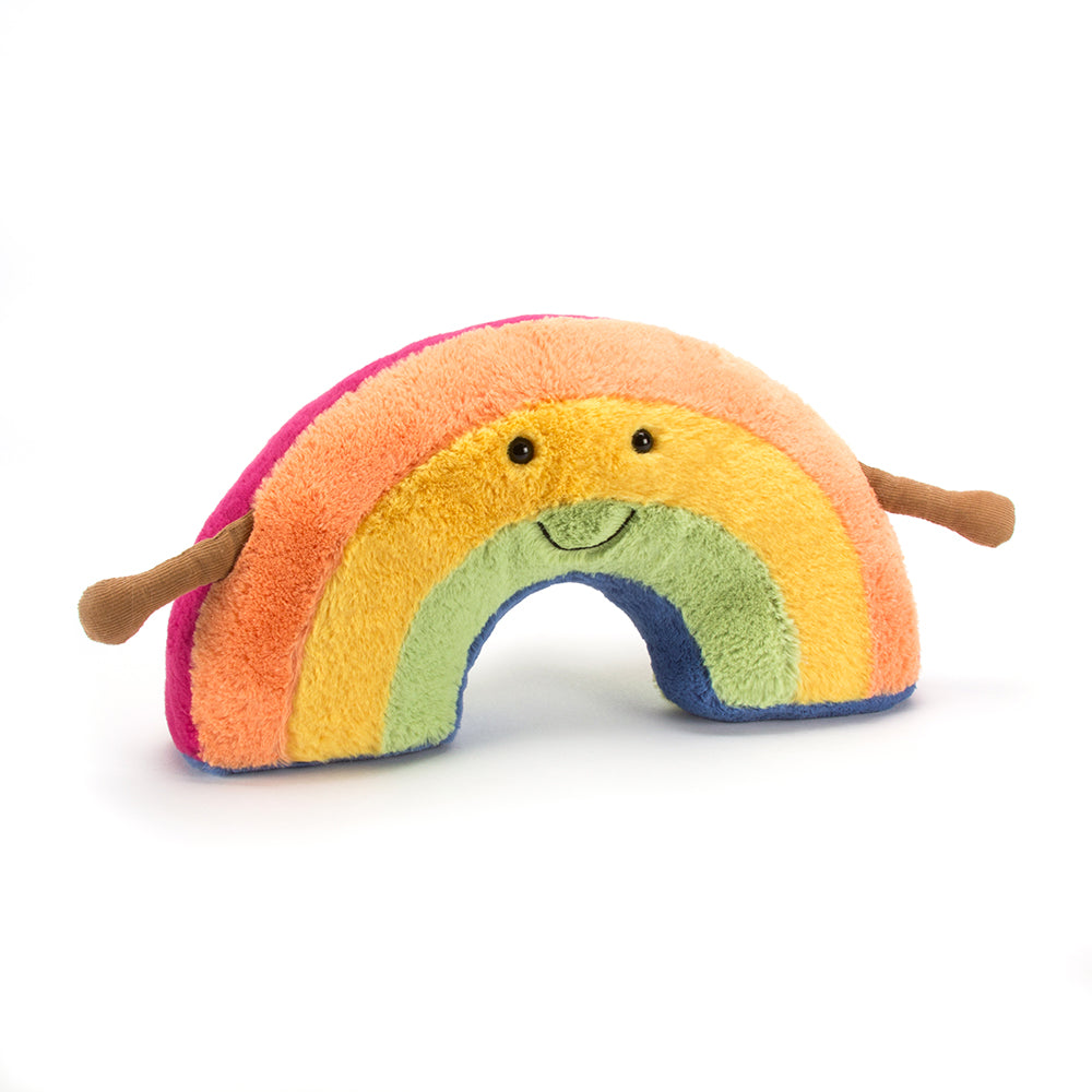 Vorderansicht: Jellycat Amuseables Rainbow – stehender Regenbogen aus Plüsch mit bunten Farben, lachendem Gesicht, schwarzen Knopfaugen und braunen Ärmchen.