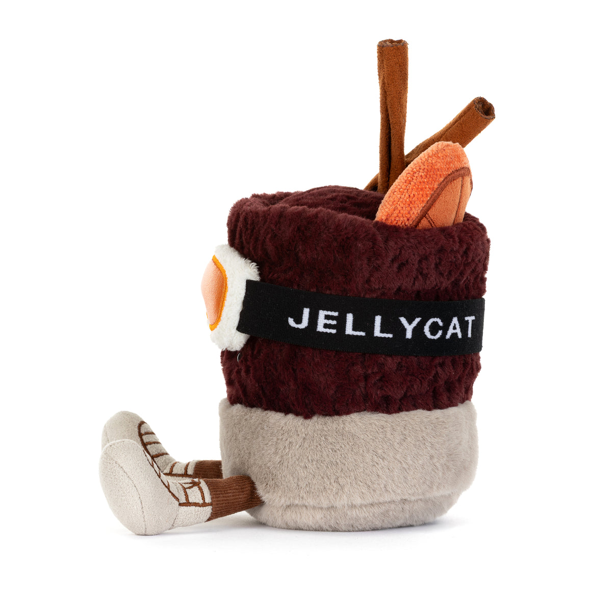 Jellycat Amuseables Mullover Spiced Drink sitzend mit Füßchen, Skibrille, Ohrenschützern, Zimtstange, Orangenscheibe und Jellycat-Schriftzug auf dem Skibrillenband von der Seite