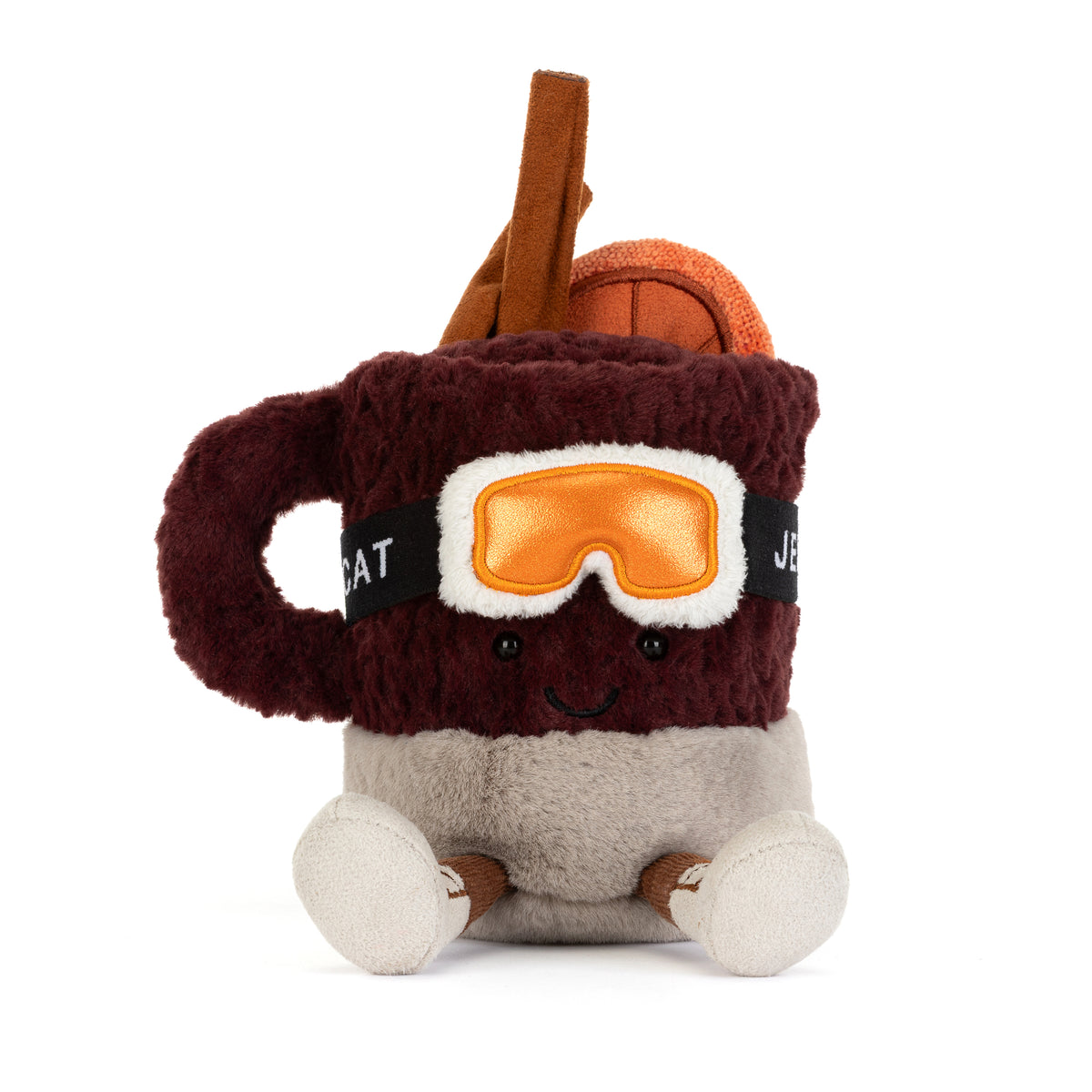 Jellycat Amuseables Mullover Spiced Drink sitzend mit Füßchen, Skibrille, Ohrenschützern, Zimtstange, Orangenscheibe und lachendem Gesicht von vorne