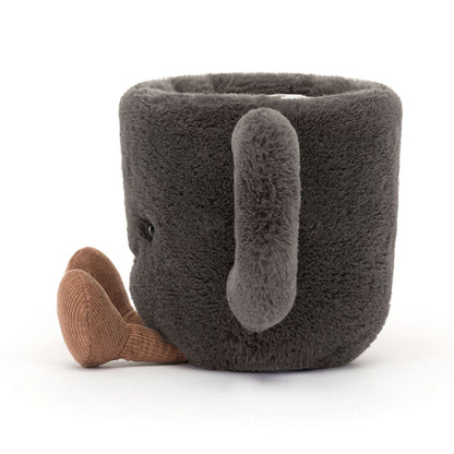 Jellycat Amuseables Coffee Cup – kuschelweiche, dunkelgraue Kaffeetasse mit kleinen Beinchen, sitzend von der Seite.