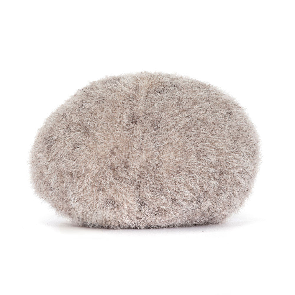 Jellycat Amuseables Pebble sitzt entspannt mit ausgestreckten Füßen und sanftem Lächeln – ein ruhiger, kleiner Kuschelbegleiter