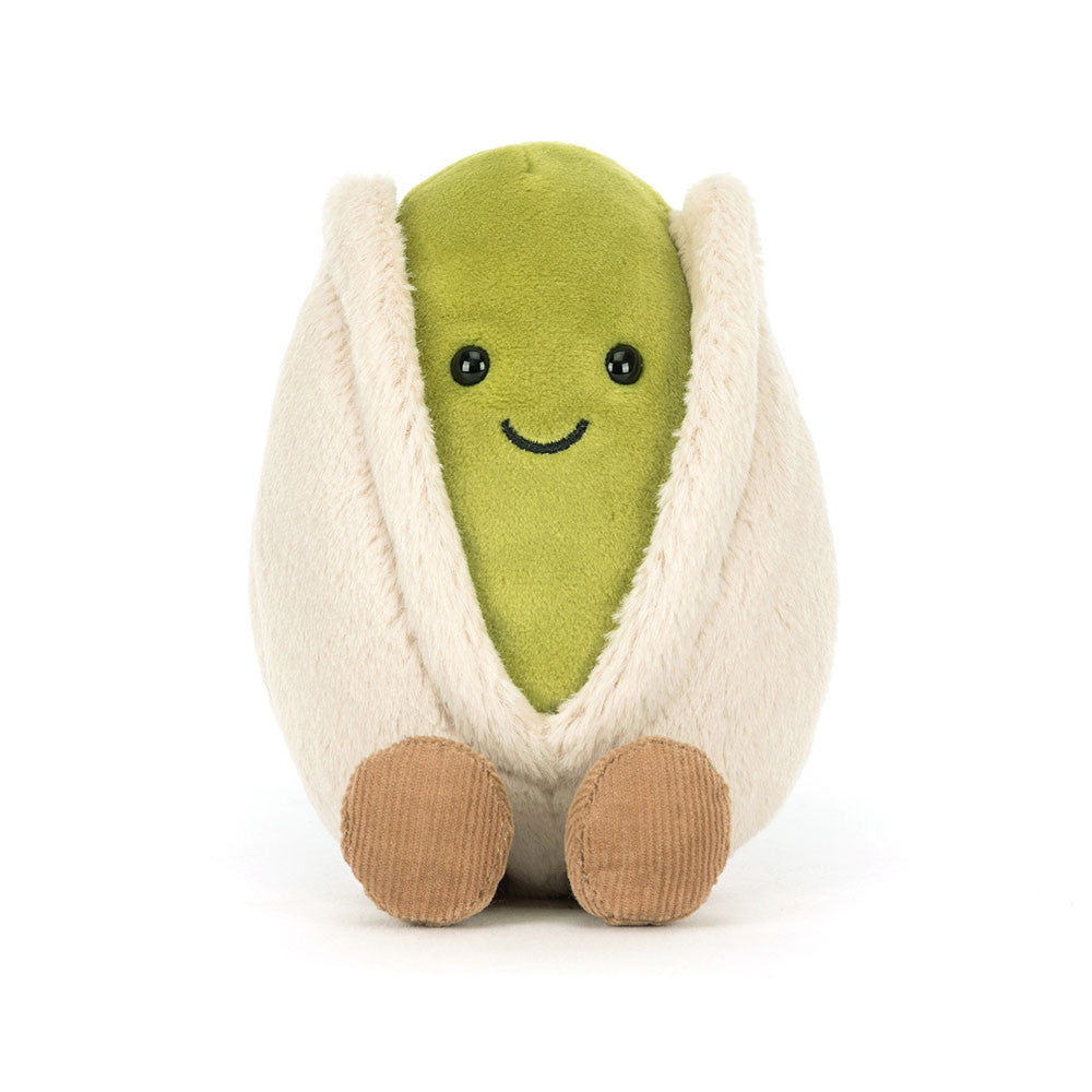 Voderansicht Jellycat Amuseables Pistachio – sitzende grüne Plüsch-Pistazie mit lachendem Gesicht und schwarzen Knopfaugen, die aus einer hellbeigen Hülle schaut und hellbraune Füßchen hat.