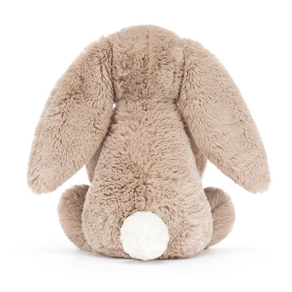 Rückansicht: Jellycat Bashful Beige Bunny Birthday – sitzender beiger Kuscheltier-Hase mit Hängeohren und kleinem Geburtstagskuchen und Kerze in den Pfoten.