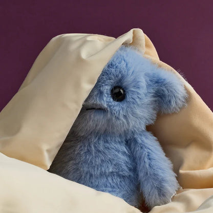 Blaues Bluemoo ECO Plüschtier mit Hörnern versteckt sich halb hinter einem Tuch