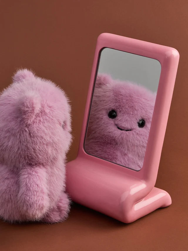 Bon Ton Toys Glimpy ECO 25 cm aus der Kollektion The Moods – lilafarbenes, flauschiges Plüschtier mit kleinem, zufriedenen Lächeln, aus recycelten Materialien schaut sich in einem rosa Spiegel an