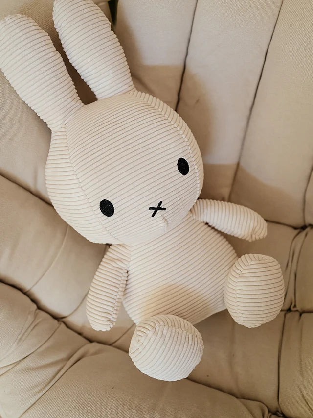 Große Miffy ECO Corduroy in Offwhite sitzt auf einem beigefarbenen Sessel, kuschelweiche XXL-Miffy von Bon Ton Toys.