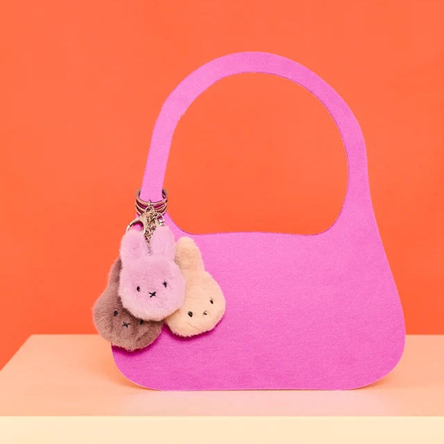 Drei Miffy ECO Fuzzy Schlüsselanhänger in verschiedenen Farben hängen an einer Tasche