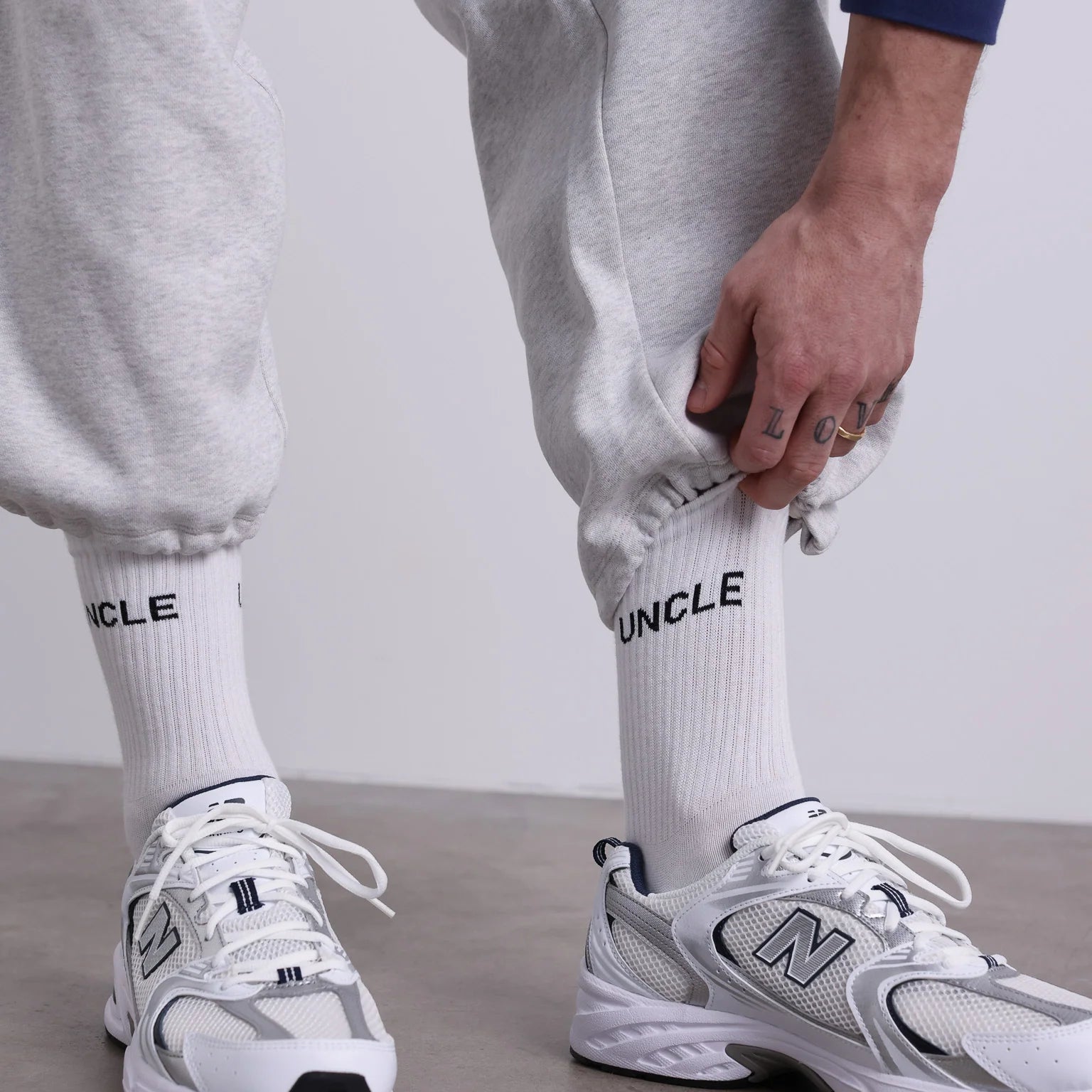 Weiße UNCLE Socken mit schwarzem Schriftzug, klassisches Socken-Design aus Baumwollmischung, flach liegend fotografiert.