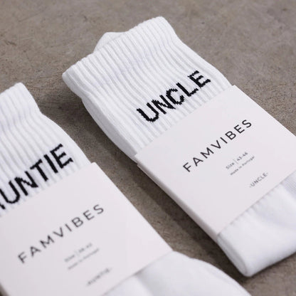 Weiße UNCLE Socken mit schwarzem Schriftzug, klassisches Socken-Design aus Baumwollmischung, flach liegend fotografiert.