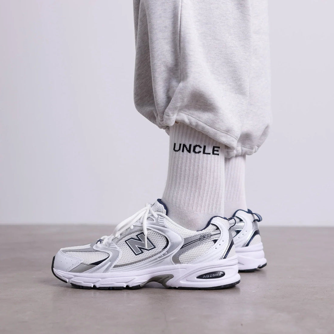 Weiße UNCLE Socken mit schwarzem Schriftzug, klassisches Socken-Design aus Baumwollmischung, flach liegend fotografiert.