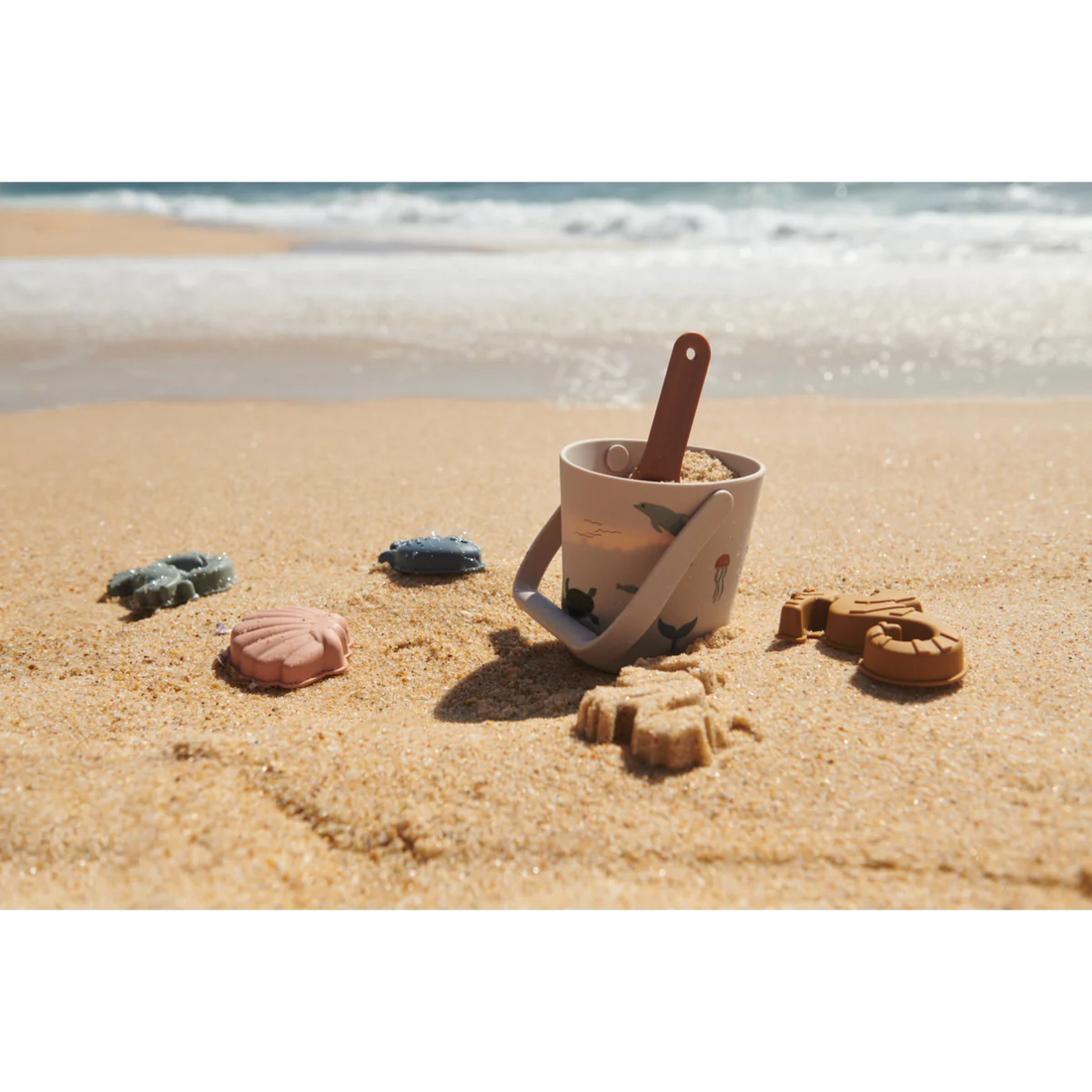 Strandspielzeug Set Gilma Meerestiere von Liewood bestehend aus Eimer, Schaufel und vier Sandförmchen (Muschel, Seepferdchen, Krebs, Fisch).