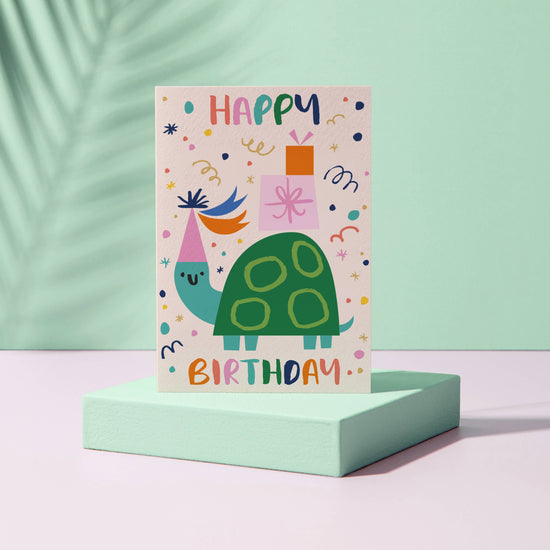 Grußkarte mit Umschlag: Happy Birthday Schriftzug und einer feiernden Schildkröte.