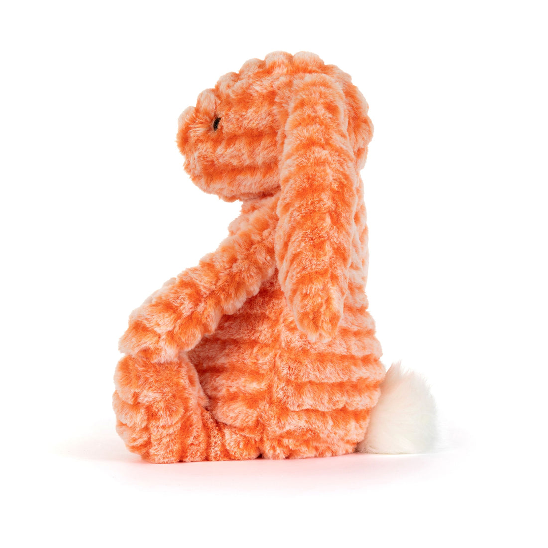 Seitenansicht: Jellycat Fizzleskip Bunny in knalligem Orange mit welligem Plüsch, Hängeohren und weißem Puschelschwanz
