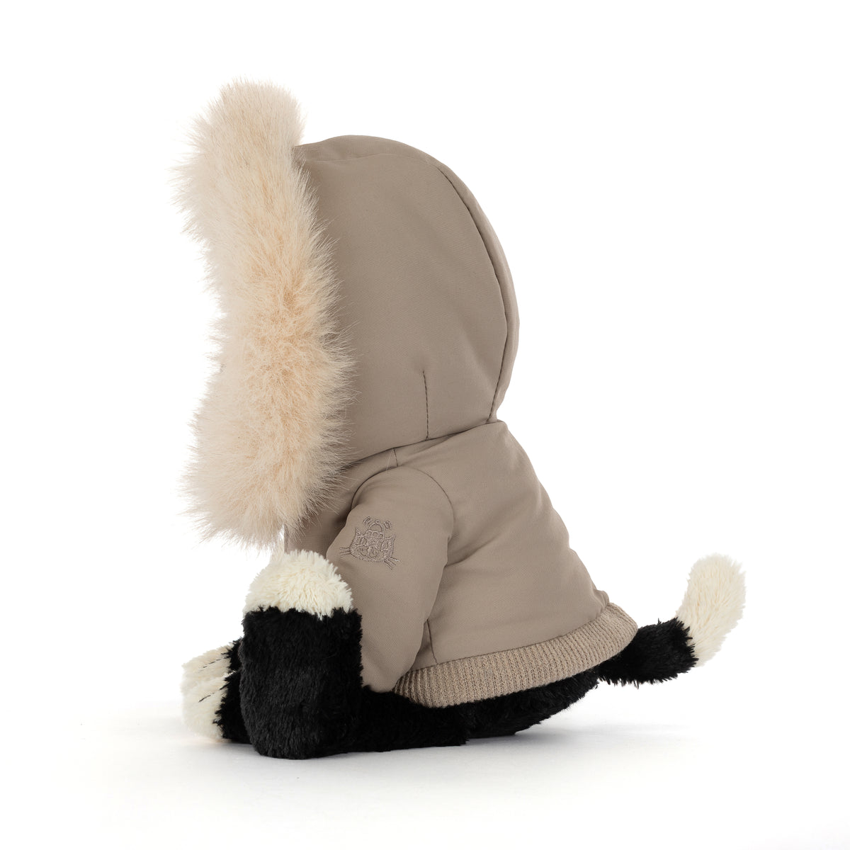 Jellycat Jack Alpine mit beigefarbener Winterjacke und großer, flauschiger Kapuze mit Fellbesatz – schwarzer Kuschelkater im winterlichen Look, von der Seite.