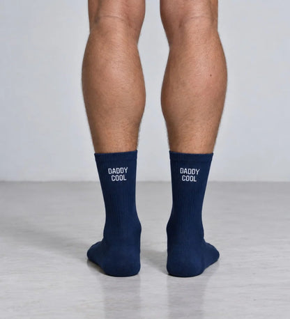 Dunkelblaue Herrensocken DADDY COOL von No Bad Days Club mit weißem Schriftzug, an den Füßen getragen.