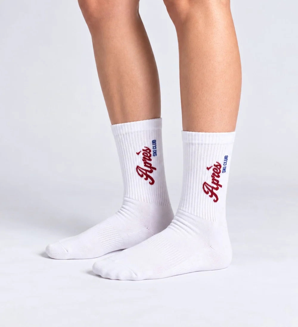 Weiße Unisex-Socken Après Ski Club von No Bad Days Club mit rotem Schriftzug, an den Füßen getragen.
