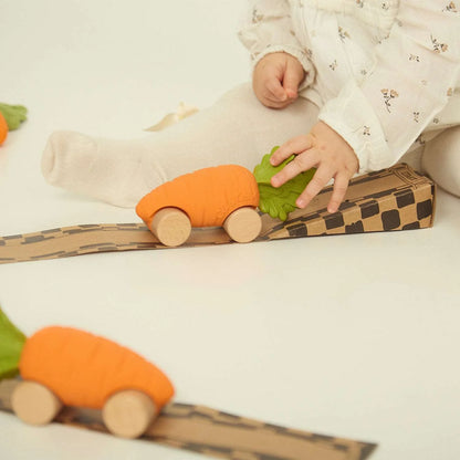 Baby spielt mit Cathy the Carrot auf der Karton-Fahrbahn der Verpackung