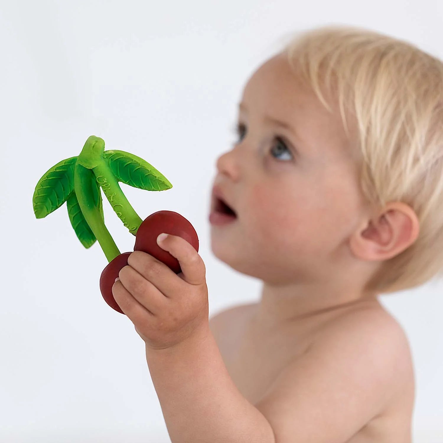 Kleines Kind hält Mery the Cherry Beißring aus Naturkautschuk in der Hand