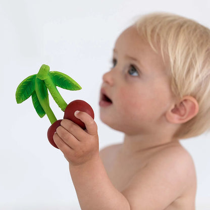 Kleines Kind hält Mery the Cherry Beißring aus Naturkautschuk in der Hand