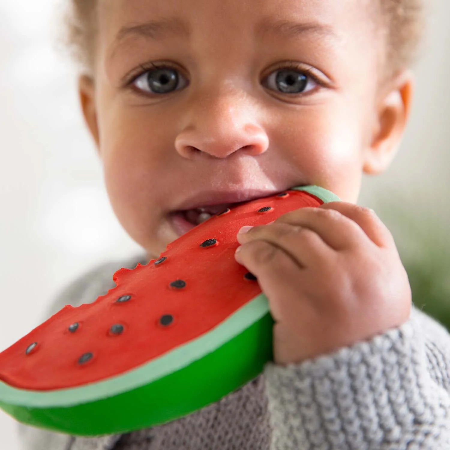 Kleiner Junge kaut auf dem Wally the Watermelon Beißring aus Naturkautschuk