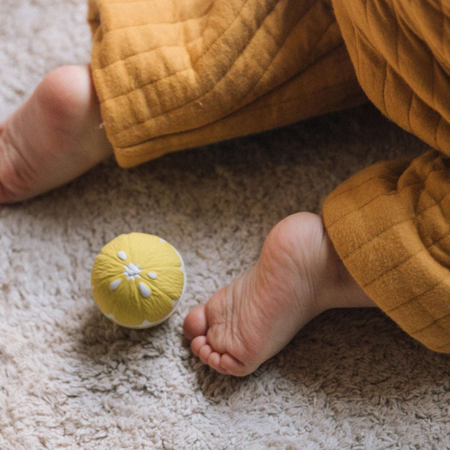 Babyfüße beim Krabbeln neben dem Zitronen-Sensorikball