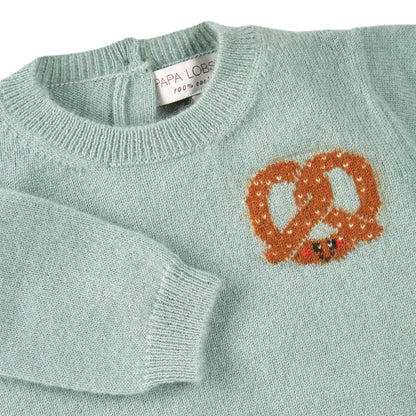 Detailansicht: Kaschmirpullover Brezel von PAPA LOBSTER in Salbei mit kleiner Brezel auf der Brust für Babys und Kinder