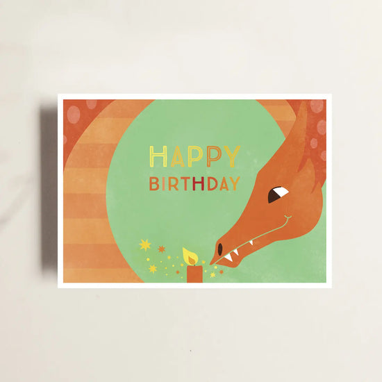 Postkarte Happy Birthday Drache der eine Kerze mit seinem Zauberatem anzündet.