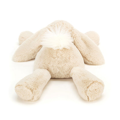 Rückansicht: Jellycat Smudge Rabbit – liegender hellbeiger Kuschelhase mit langen Hängeohren, ausgestreckten Beinen und Kopf auf den Vorderpfoten. Mit kleinen schwarzen Knopfaugen und weißem Puschelschwanz.