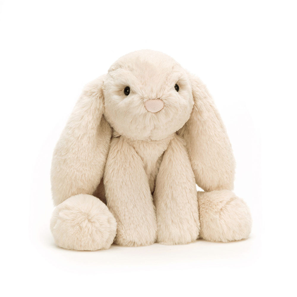 Vorderansicht: Jellycat Smudge Rabbit – liegender hellbeiger Kuschelhase mit langen Hängeohren, ausgestreckten Beinen und Kopf auf den Vorderpfoten. Mit kleinen schwarzen Knopfaugen und weißem Puschelschwanz.