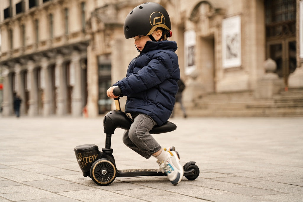 Kind fährt Scoot and Ride Highwaykick 1 Lifestyle Black Gold Kinderroller mit Sitz und Aufbewahrungsbox