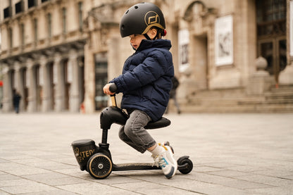 Kind fährt Scoot and Ride Highwaykick 1 Lifestyle Black Gold Kinderroller mit Sitz und Aufbewahrungsbox