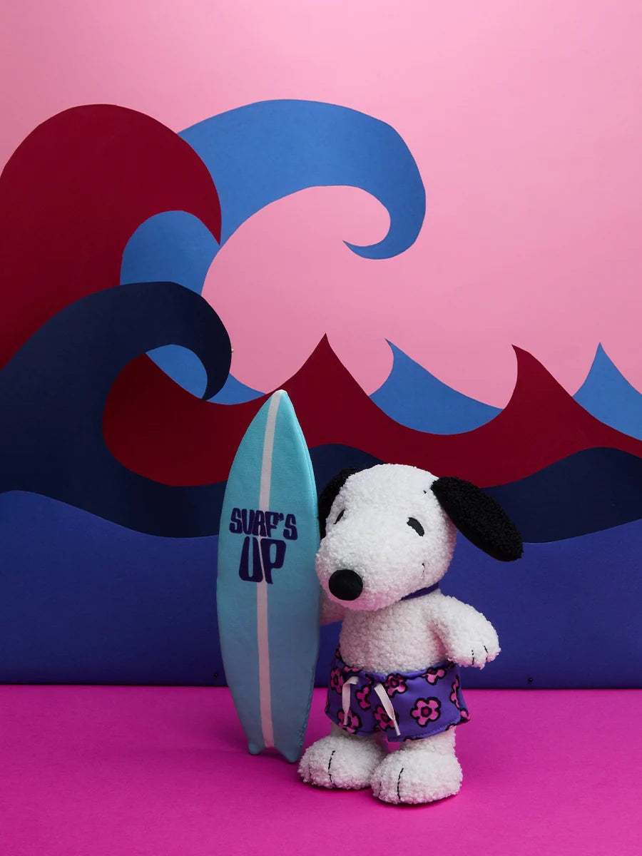 Snoopy ist am Strand mit seinem Surfbrett unterwegs. 