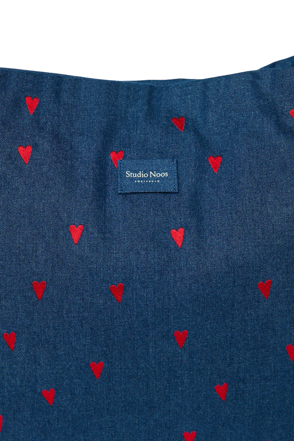 Detailansicht der Studio Noos Mom-Bag mit in dunkelblauem Demin, gestickten roten Herzen und Studio Noos Logo