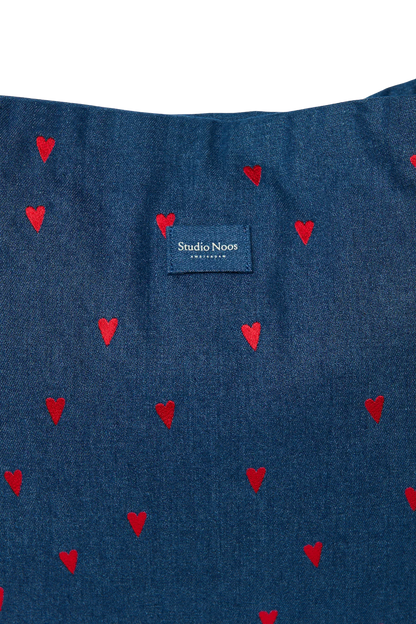 Detailansicht der Studio Noos Mom-Bag mit in dunkelblauem Demin, gestickten roten Herzen und Studio Noos Logo