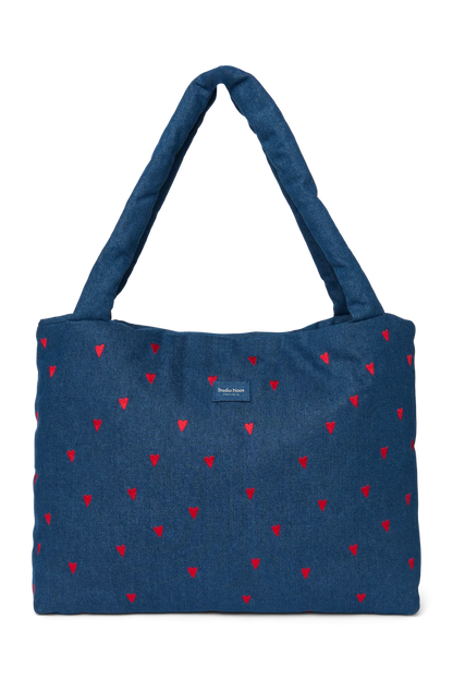 Vorderansicht der Studio Noos Mom-Bag mit wattierten Henkeln, in dunkelblauem Denim, gestickten roten Herzen und Studio Noos Logo.