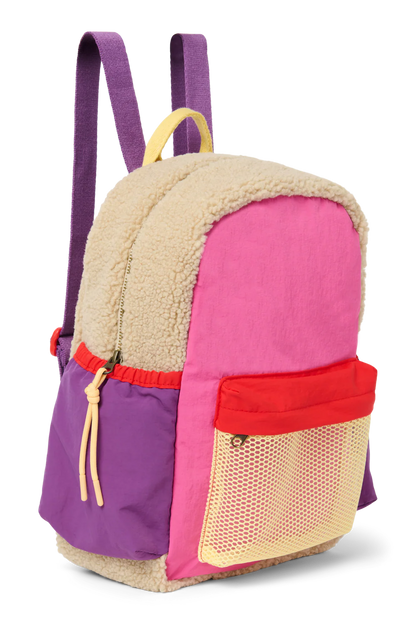 Seitenansicht: Studio Noos Patchwork Midi-Rucksack l Bright Pink in bunten Farben mit beigem Teddy-Stoff an den Seiten und an der Rückseite, pinken Patchwork-Details und lila-rot-beigen Akzenten