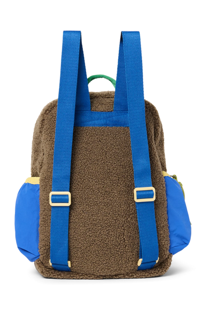 Rückansicht: Studio Noos Patchwork Mini-Rucksack l Fiery Red in bunten Farben mit braunem Teddy-Stoff, roten Patchwork-Details und blau-grün-gelben Akzenten. Hinten brauner Teddystoff und blaue verstellbare Träger
