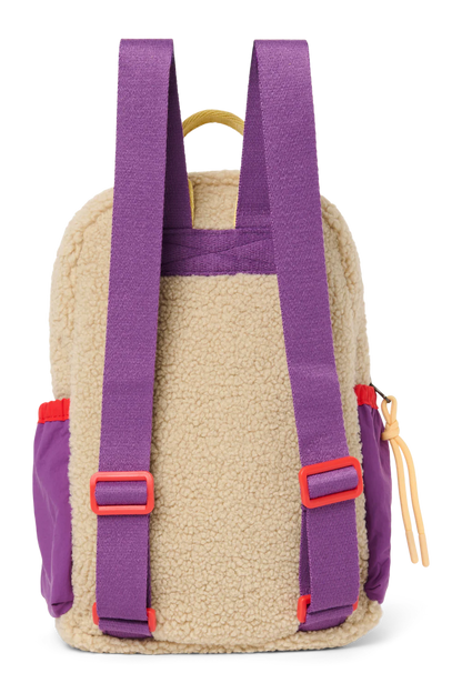 Rückansicht: Studio Noos Patchwork Mini-Rucksack l Bright Pink mit Reissverschluss-Mesh-Tasche vorne und seitlichen Taschen. In bunten Farben mit beigem Teddy-Stoff, Patchwork-Details mit pink-rot-lila-beigen Akzenten. Lila Träger verstellbar und an der Rückseite ausschließlich beiger Teddystoff.